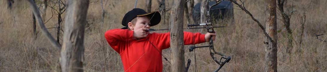 A young boy taking aim on the archery range.